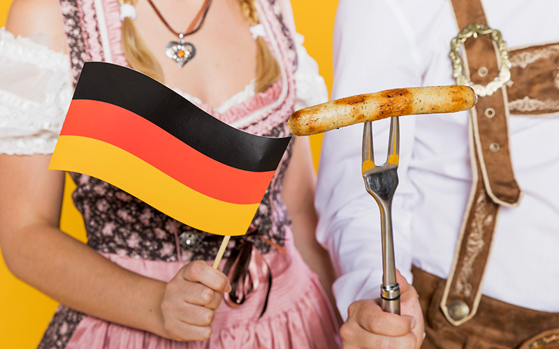 Девушка и парень держат немецкий флаг и сосиску, фото
